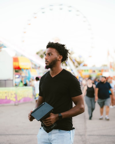 man in black crew neck t-shirt holding black tablet computer
